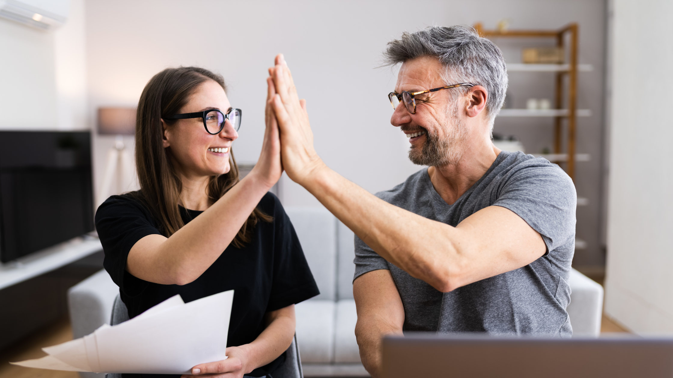 A woman and a man high fiving to celebrate income tax cuts.